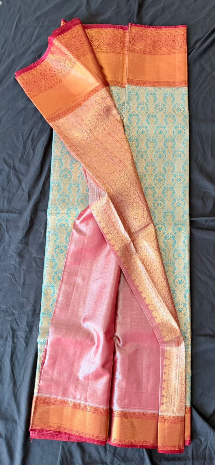 Cream Kanchipuram silk saree with floral and geometric motifs in teal and gold, orange-gold border with coral-pink accents, draped product view