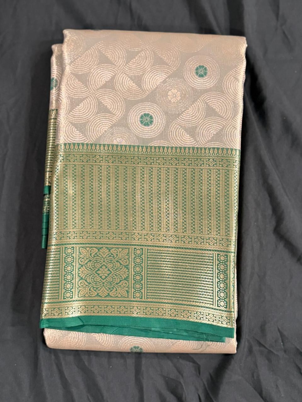 Cream Kanchipuram silk saree with geometric butta motifs and teal green-gold border, folded detail view