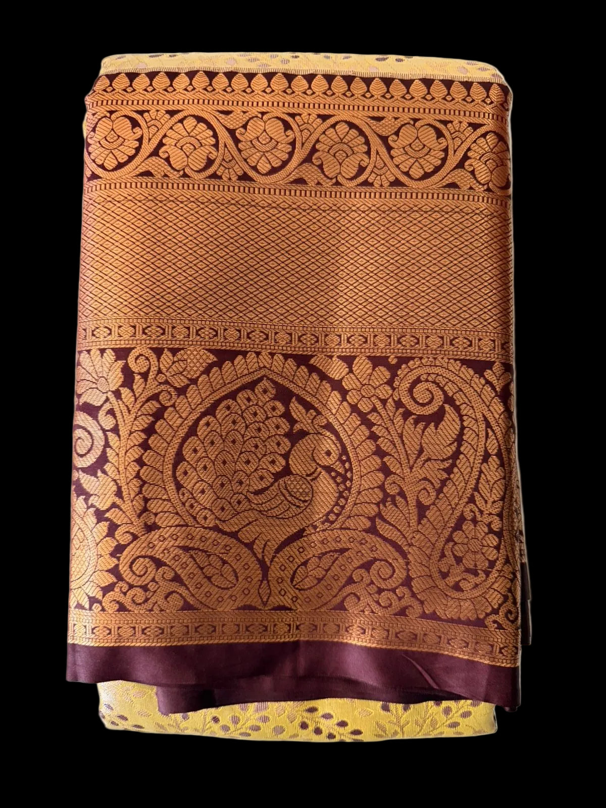 Warm mustard gold Kanchipuram silk saree with scattered butta motifs and ornate brown-gold border, folded detail view