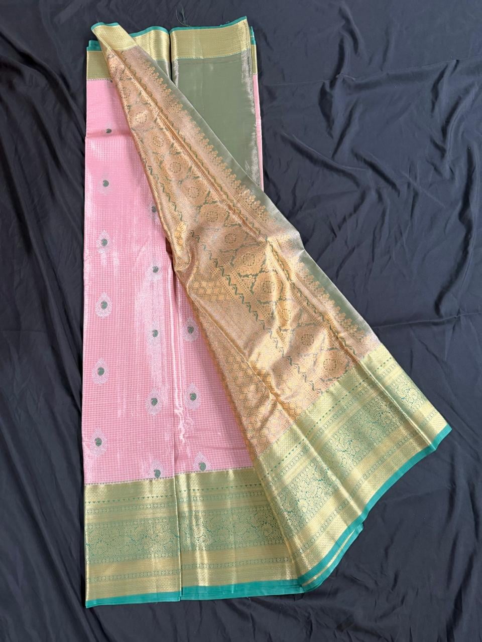 Adult South Asian woman wearing light pink Kanchipuram silk saree with butta and geometric motifs and ornate gold border