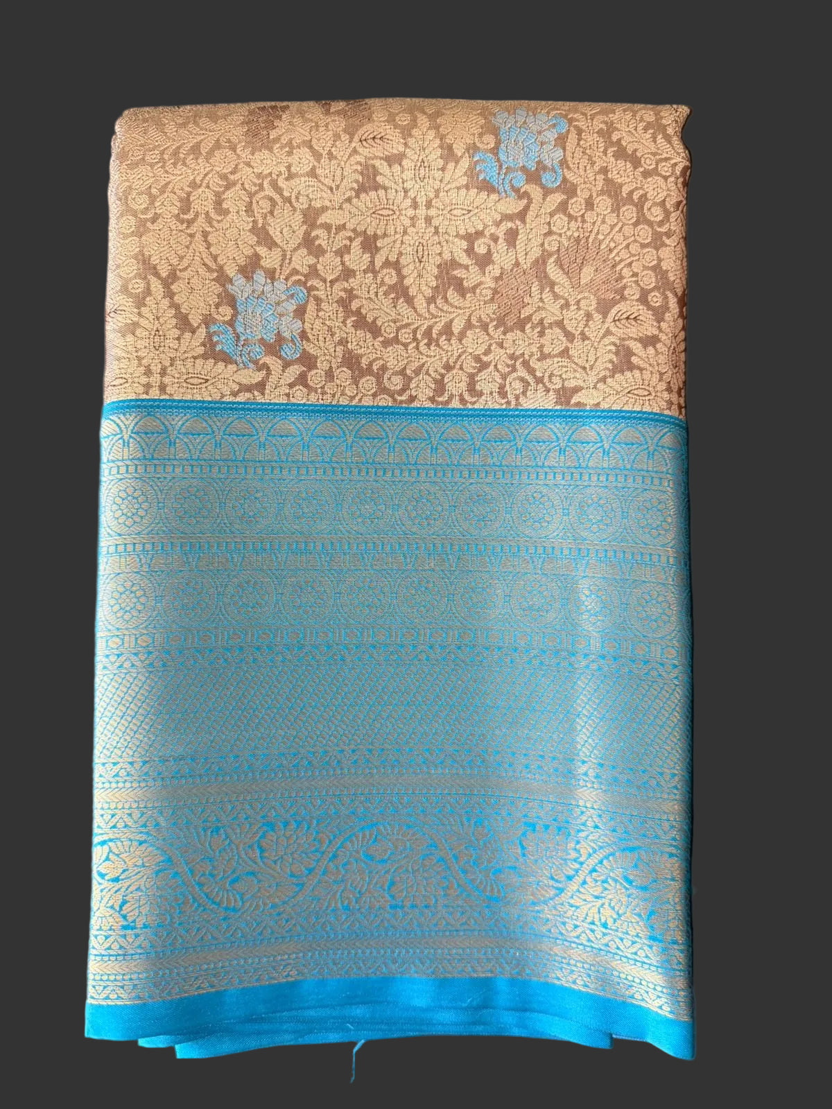 Cream beige Kanchipuram silk saree with floral paisley damask pattern and blue-gold woven border, folded detail view