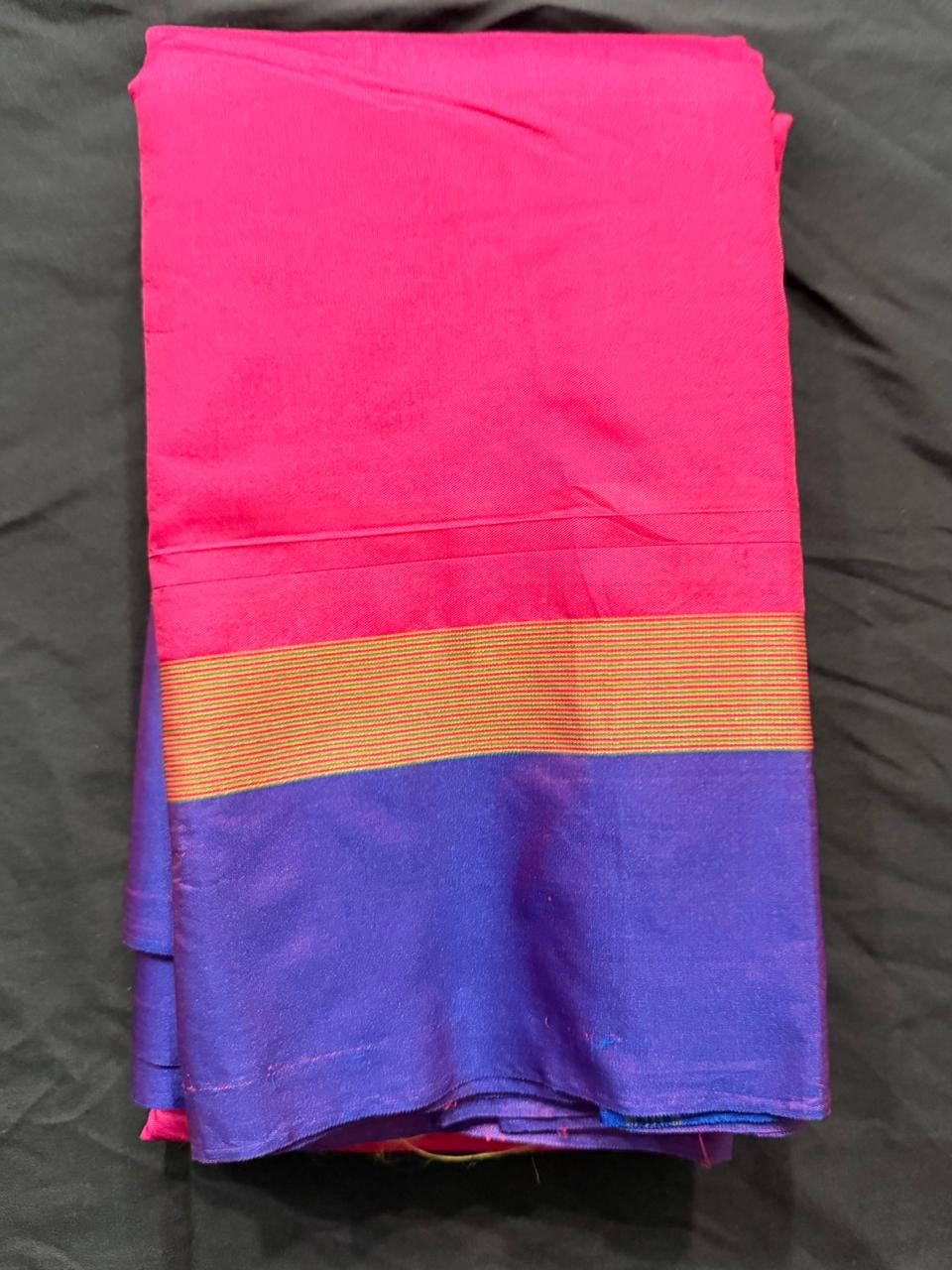 Hot pink color-block saree with royal purple and cobalt blue sections, gold striped border and purple pallu, folded detail view