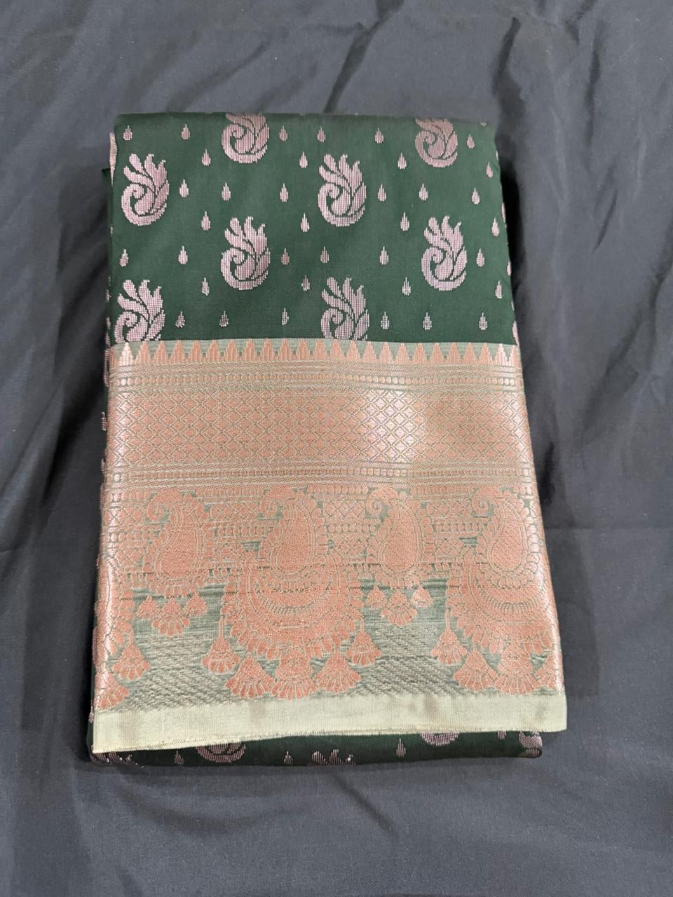 Forest green saree with paisley and butta motifs and ornate gold border, folded detail view